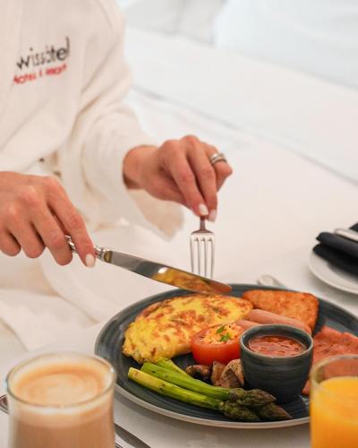 a person cutting a plate of food with a knife and fork at Swissôtel Al Murooj Dubai in Dubai
