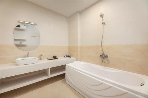 a bathroom with a tub and a sink and a mirror at Fuji Hanoi Hotel and Apartment West Lake in Hanoi