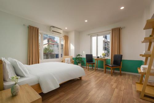 a bedroom with a white bed and a table and chairs at Fuji Hanoi Hotel and Apartment West Lake in Hanoi
