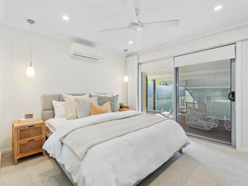 a white bedroom with a large bed and a balcony at The Chill House - Heated Pool - Entertainment Area in Gold Coast