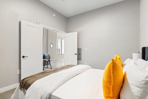 a white bedroom with a bed and a chair at Spacious 2BR CozySuites OTR Downtown #08 in Cincinnati
