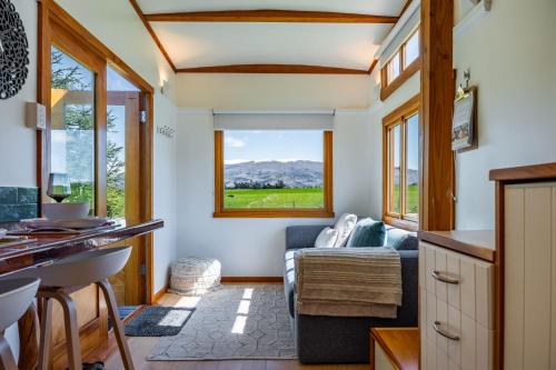 Il dispose d'une cuisine et d'un salon avec un canapé et une fenêtre. dans l'établissement Tarras Tiny Haven - Wake up to Breathtaking Mountains, à Tarras
