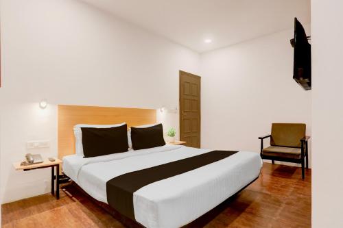 a bedroom with a large bed and a chair at Townhouse Nagpur Junction Formerly Hotel Woodland in Nagpur
