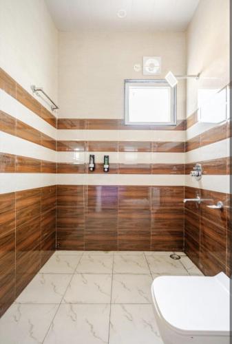 a bathroom with wooden walls and a toilet and a window at The Royal Harmony in Greater Noida