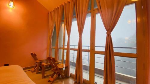 a bedroom with a large window with orange curtains at Athiti Kunj Eco Adventure Retreat in Mukteswar
