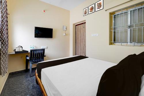 a bedroom with a bed and a desk and a window at Hotel O Karanodai Formely AVR Rooms 