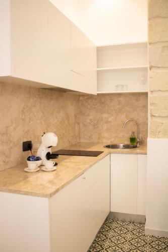 a kitchen with white cabinets and a sink at BADIA NUOVA Apart Hotel in Trapani