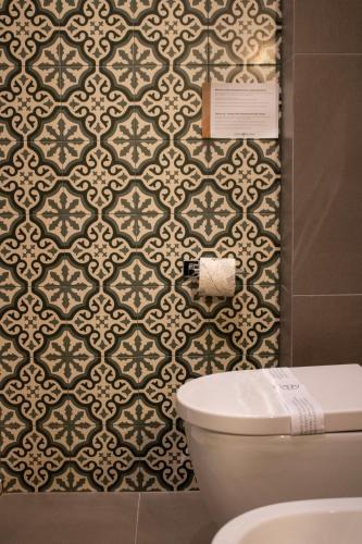 a bathroom with a toilet and a wall at BADIA NUOVA Apart Hotel in Trapani