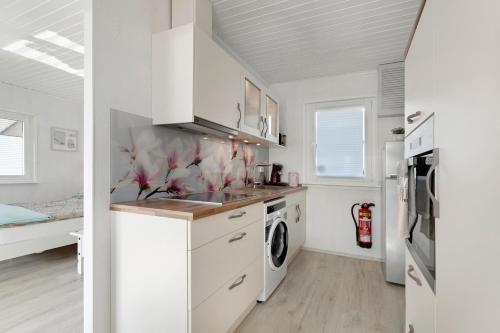 a kitchen with white cabinets and a washer and dryer at Kleines Schweden in Hennstedt