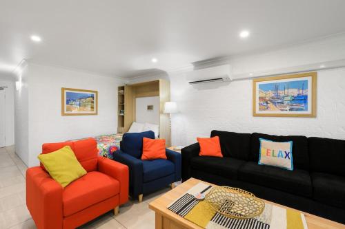 a living room with a couch and two chairs and a bed at Paradise at The Bay in Nelson Bay