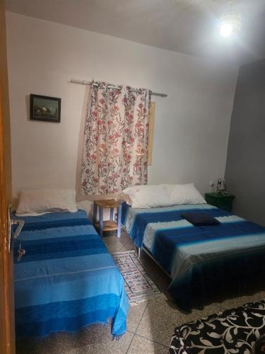 a bedroom with two beds and a curtain at La maison des amis in Taroudant