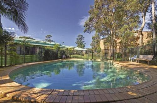 a swimming pool in a yard with a fence at Paradise at The Bay in Nelson Bay