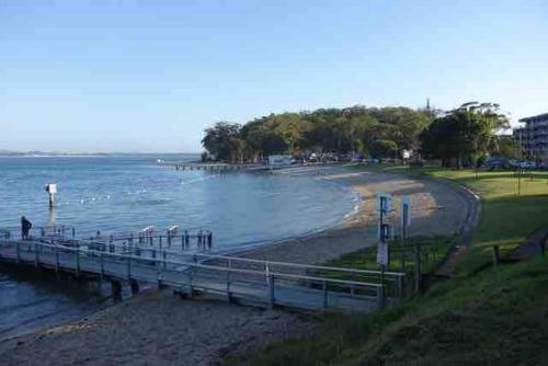 a beach with a pier next to the water at Paradise at The Bay in Nelson Bay