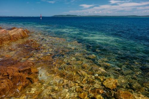 a large body of water with rocks and a lighthouse at Paradise at The Bay in Nelson Bay