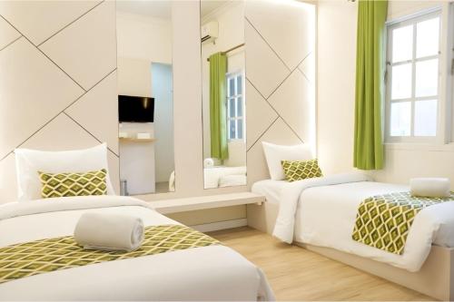 a bedroom with two beds and a mirror at Sukun Boutique Hotel Cilacap Managed by GHM in Cilacap