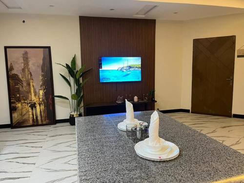een lobby met een tafel met een tv aan de muur bij ASNB Residences-F4 in Multan