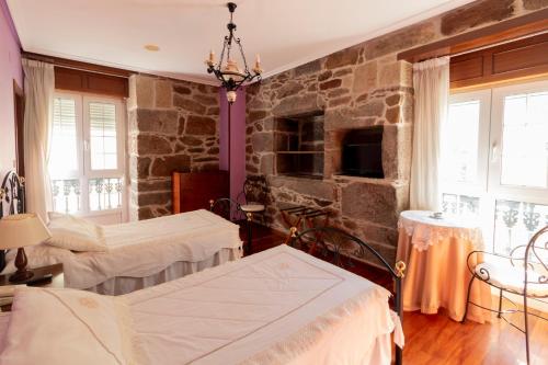ein Schlafzimmer mit zwei Betten und einer Steinwand in der Unterkunft Hotel Pousada Vicente Risco in Castro Caldelas