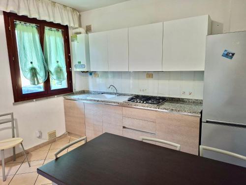 a kitchen with white cabinets and a table and a refrigerator at ISA - Felci 19, apartment 6 beds in Marina di Bibbona just 300 mt from the sea in Marina di Bibbona