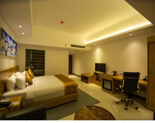 Una habitación de hotel con una cama y un escritorio con una computadora. en Hotel X Rajshahi, en Rājshāhi