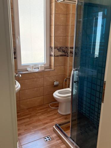 a bathroom with a toilet and a glass shower at Studio holidays in Shëngjin