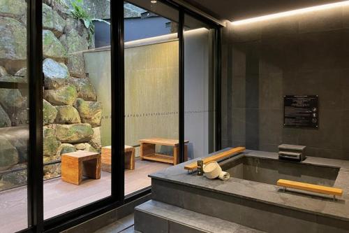 a bathroom with a tub with a stone wall at Onsen Papawaqa in Taian