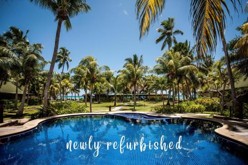 a swimming pool with palm trees in the background at Paradise Sun Hotel Seychelles in Baie Sainte Anne
