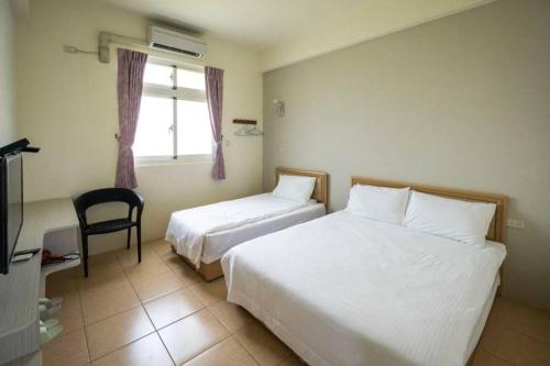 a hotel room with two beds and a chair at 白宮七哩香園民宿 in Hou-p'an-ts'un