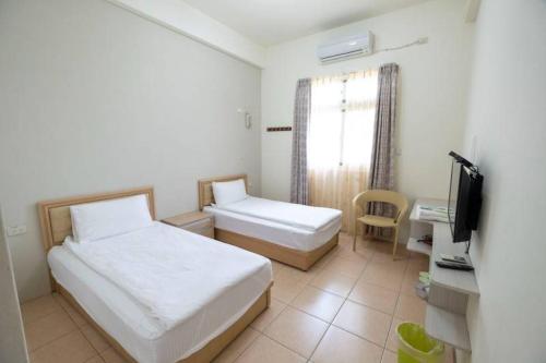 a hotel room with two beds and a television at 白宮七哩香園民宿 in Hou-p'an-ts'un