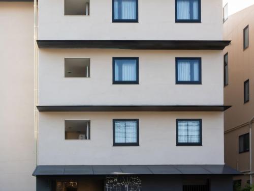 un alto edificio bianco con finestre nere di hotel anddoggy Kyoto Nijo a Kyoto