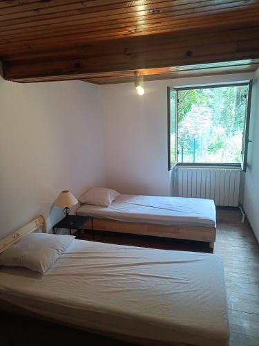 two beds in a room with a window at Maison Ancienne Albies in Albiès