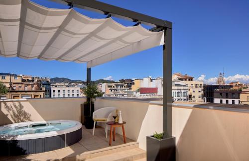 a rooftop patio with a hot tub and a white umbrella at ME Barcelona in Barcelona