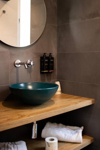 a bathroom with a green bowl sink on a wooden shelf at BADIA NUOVA Apart Hotel in Trapani