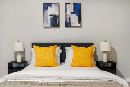 un letto con 2 cuscini gialli e 2 lampade di CozySuites Modern 3BR OTR District #17 a Cincinnati