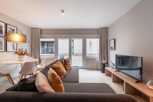a living room with a couch and a tv at Ostend Central Residence in Ostend