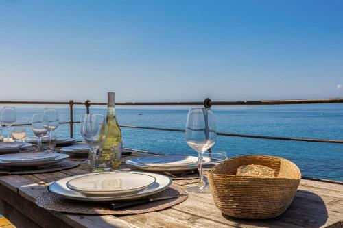 a table with wine glasses and plates and a basket at Maison de pêcheur dans le Cap Corse in Erbalunga