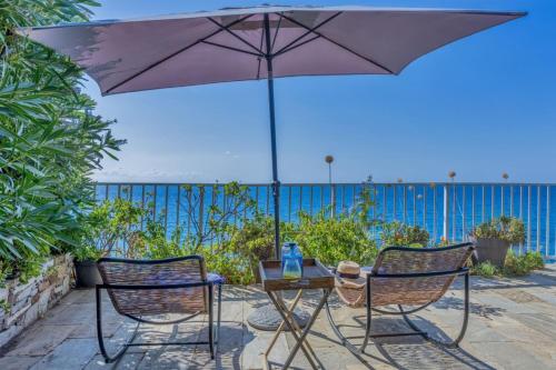 2 Stühle und ein Tisch mit Sonnenschirm in der Unterkunft Casetta Ricci - Les Azedarachs II in Erbalunga