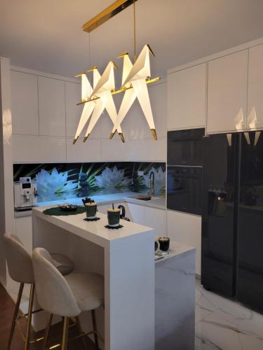a kitchen with white cabinets and a chandelier at Apartament JOANNA in Owczary