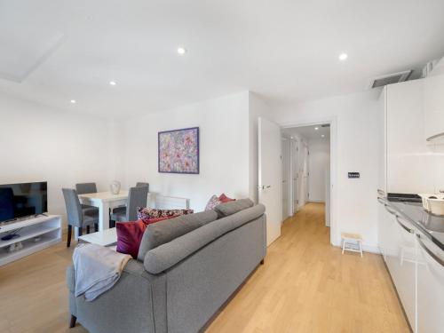 a living room with a gray couch and a kitchen at Pass the Keys Bright and cozy apartment in Kentish Town in London