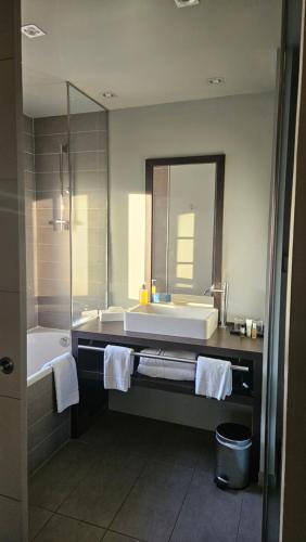a bathroom with a sink and a tub and a mirror at Hotel du Fronton in Bidart