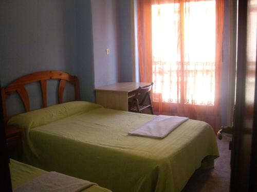 a bedroom with two beds and a table and a window at Hostal Pacios in Madrid