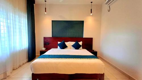 a bedroom with a large bed with blue pillows at Citadel Boutique Hotel Thekkady in Jāmb