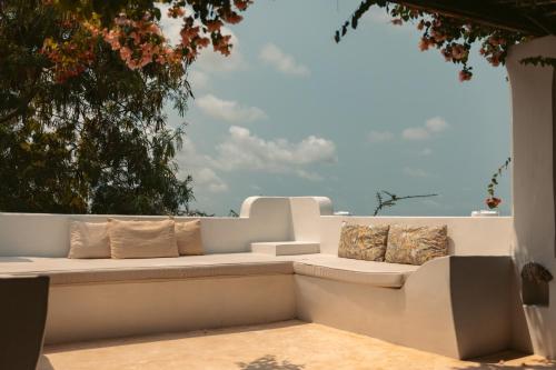 a white bench sitting on a wall with pillows at Banana House and Wellness Centre in Lamu