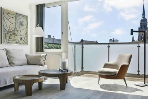 a living room with a couch and a table and a chair at Elite Penthouse prime location in Copenhagen