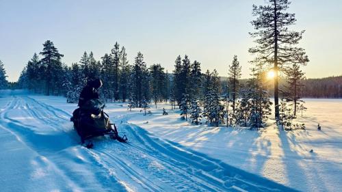 a person riding a snowmobile down a snow covered road at Luonto, das Blockhaus in Inari
