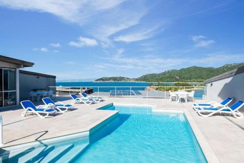 a swimming pool with lounge chairs and the ocean at Luxury Oceanview Escape in Nelly Bay