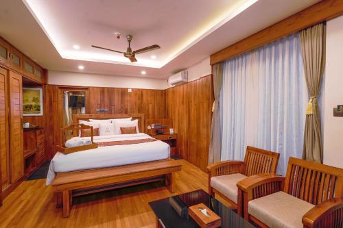 a bedroom with a bed and two chairs in it at Chandys Drizzle Drops - Munnar Top Station in Munnar