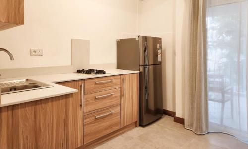 a kitchen with a stainless steel refrigerator next to a window at La Perla Holiday Apartments in Pereybere