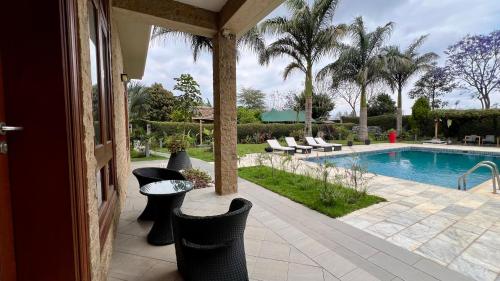a patio with a pool and chairs and a table at Uyoga House in Arusha