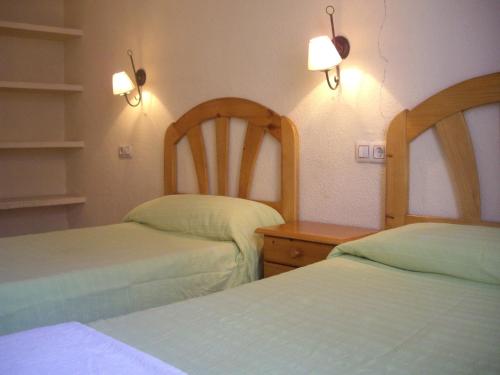 a bedroom with two beds and a dresser and lights at Hostal Pacios in Madrid
