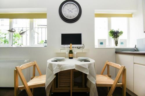 a dining room table with two chairs and a clock on the wall at Between Piers - Central- by Brighton Holiday Lets in Brighton & Hove